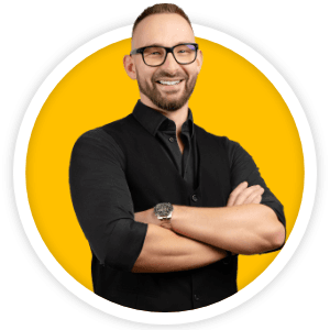 Mężczyzna w okularach stoi z założonymi rękami na tle żółtego koła, uśmiecha się.