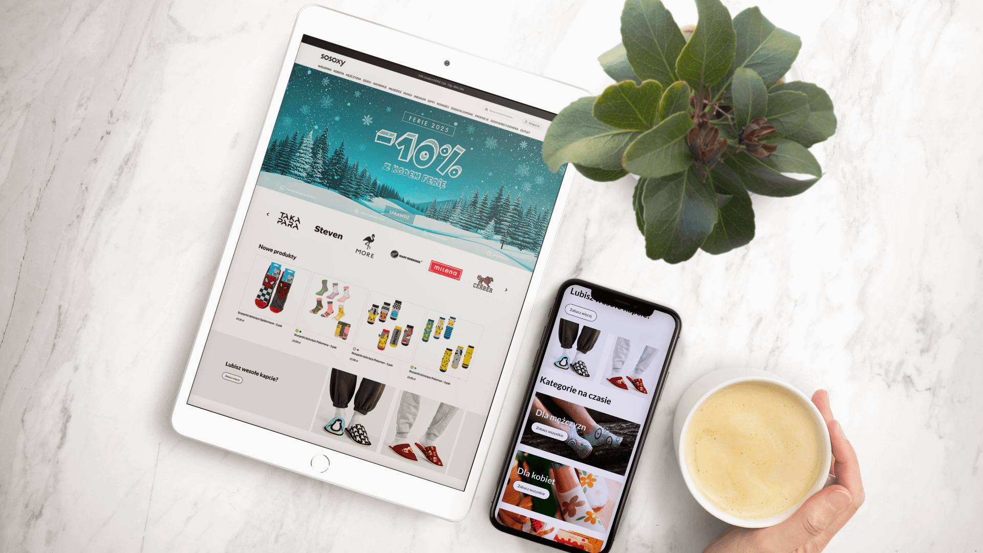 Tablet i smartfon z wyświetloną stroną sklepu internetowego, obok filiżanka kawy i roślina.
