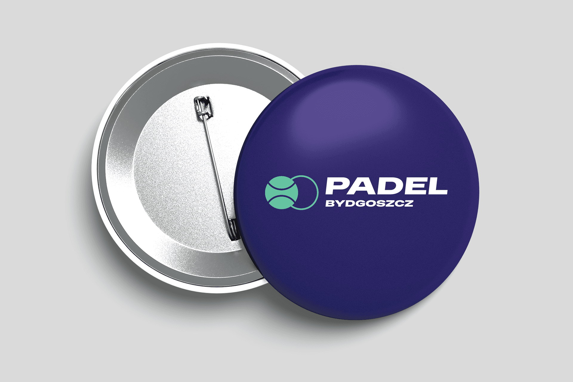 Fioletowa przypinka z napisem "Padel Bydgoszcz" i grafiką piłki na jasnym tle.